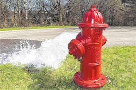 Red fire hydrant with water coming out of one side, flushing